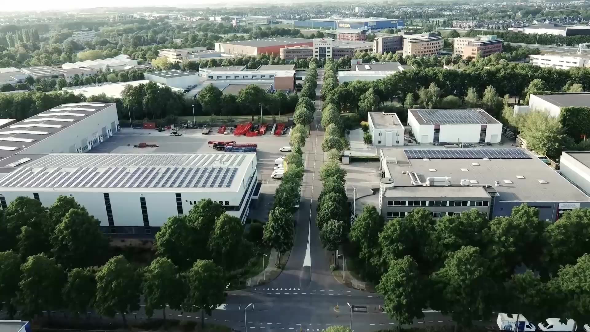Bedrijventerrein van boven, met panden, bomen en een parkeerplaats