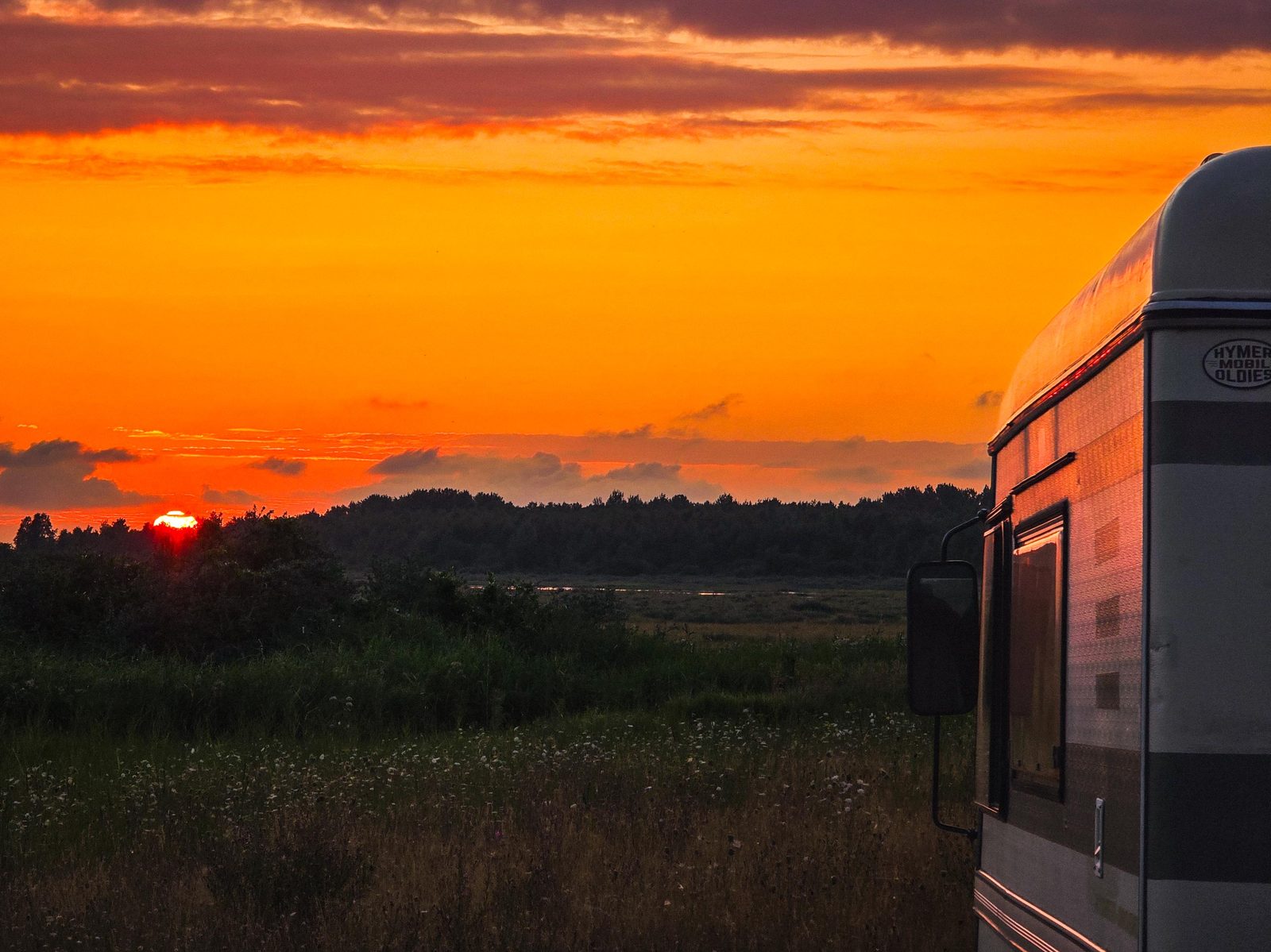 Zonsondergang boven de hei naast een camper