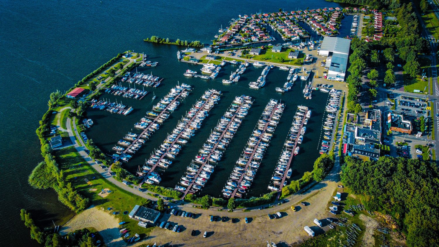 Luchtfoto van een jachthaven met lange steigers vol boten